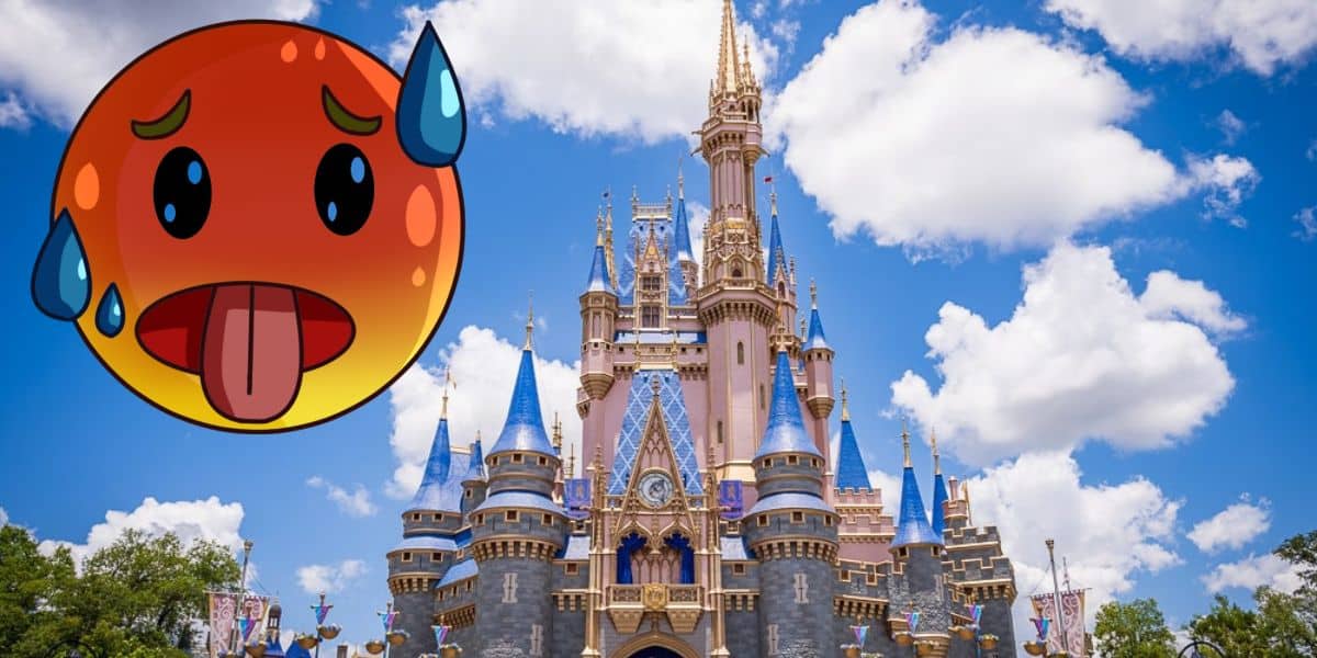 An emoji with a red face, sweat droplets, and its tongue sticking out is placed next to a fairytale castle under a bright blue sky with fluffy clouds. The image conveys a sense of heat and exhaustion, as if the character desperately needs heat relief in a magical theme park setting.