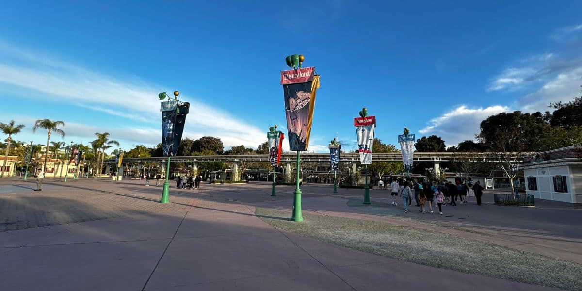 The Disneyland Resort esplanade, looking at Disneyland Park with banners of different Disney movies and attractions.