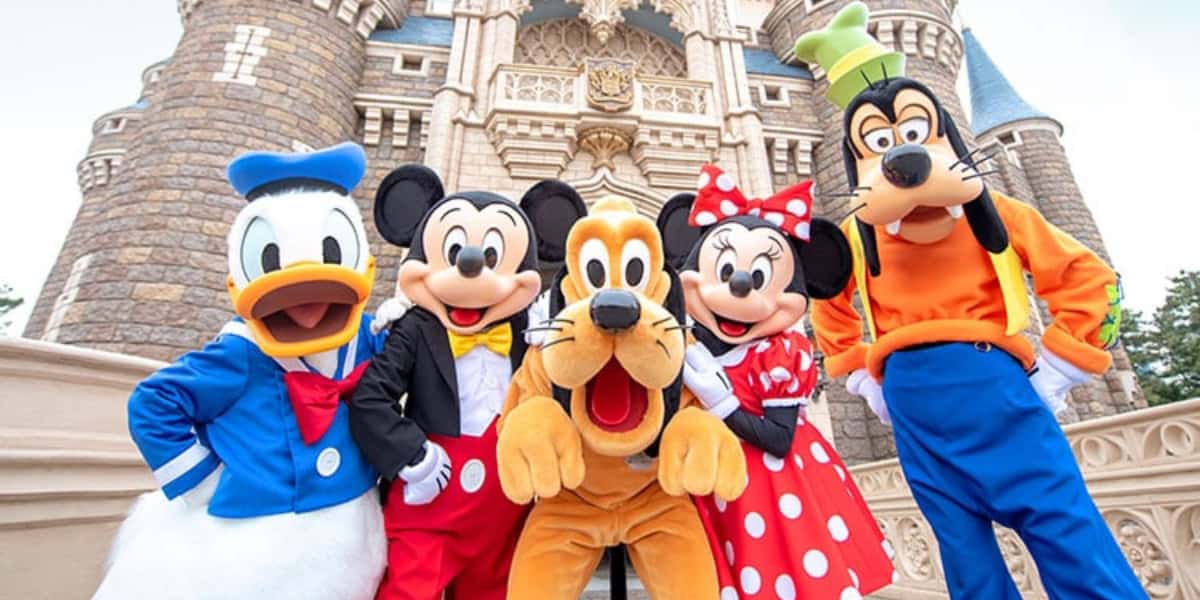 A group photo of characters in front of Cinderella Castle. From left to right: Donald Duck, Mickey Mouse, Pluto, Minnie Mouse, and Goofy.