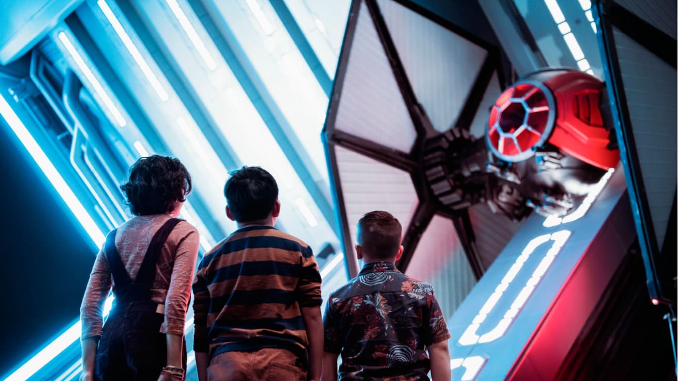 Three kids standing before a Tie Fighter at the Star Wars, Galaxy’s Edge attraction 