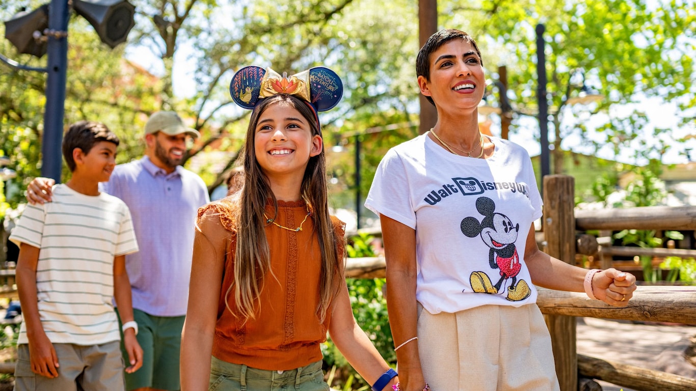 Mother and daughter holding hands and a father with his arm around his son walking through Disney’s Animal Kingdom Theme Park