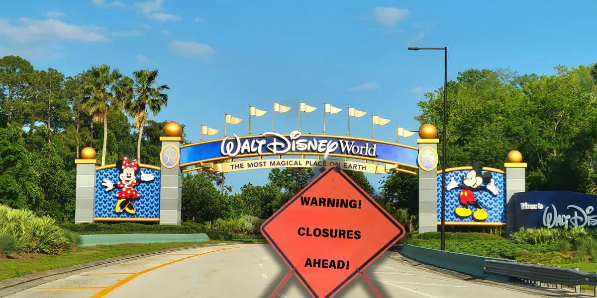 A road leading to the entrance of WDW, featuring colorful signs with Mickey and Minnie Mouse on either side. In the foreground, a bright orange warning sign reads "Warning! Closures Ahead!" against a backdrop of Disney-themed trees and a clear blue sky.