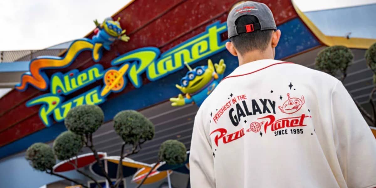 A man in a pizza planet shirt in front of Alien Pizza Planet