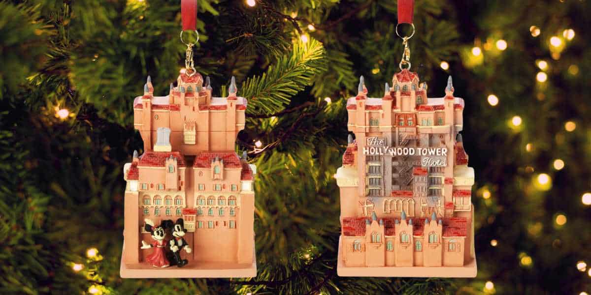 Two must-have Disney ornaments adorn the Christmas tree. One features Mickey and Minnie Mouse in front of the Hollywood Tower Hotel, while the other showcases the hotel's facade with its iconic sign. The tree sparkles with lights, making these Disney Park-themed ornaments shine even brighter.