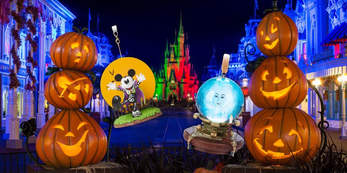 A brightly lit theme park features a pathway adorned with glowing jack-o'-lanterns. An illuminated castle stands in the background. A Mickey Mouse in costume and a Madame Leota light-up crystal ball are displayed among the spooky Disney ornaments, enhancing the festive atmosphere.