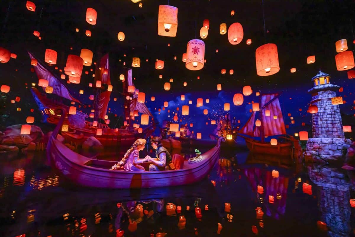 Rapunzel and Flynn Rider sitting in a boat surrounded by lanterns during a romantic scene in Rapunzel's Lantern Festival, the brand-new attraction at Fantasy Springs in Tokyo DisneySea