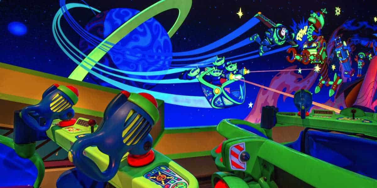 Vibrant indoor amusement ride featuring colorful space-themed cars with mounted laser guns, set against a backdrop of galaxies, planets, and animated Galactic Hero figures.