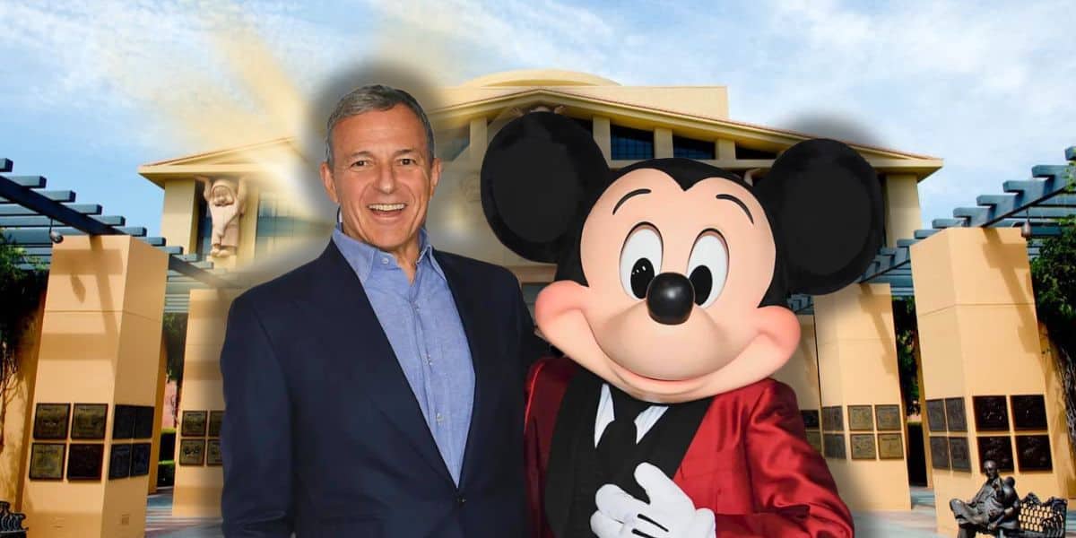 Bob Iger posing with Mickey Mouse in front of a sunny, palm-lined Company building.