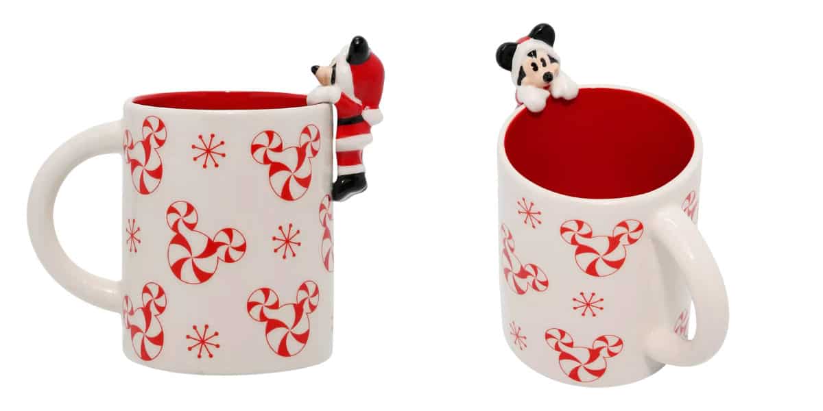 Two white Mickey Mugs with red interiors, featuring red and white peppermint candy designs resembling mouse ears. Each mug has a small Santa figure climbing on the handle, perfect for adding Disney magic to your holiday season.