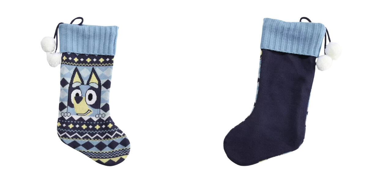 Two Christmas stockings: one featuring a cartoon dog character akin to Bluey, with blue geometric patterns, and the other in solid dark blue with a light blue cuff. Both adorned with small white pom-poms, they're as charming as festive sweaters hanging among holiday ornaments. 