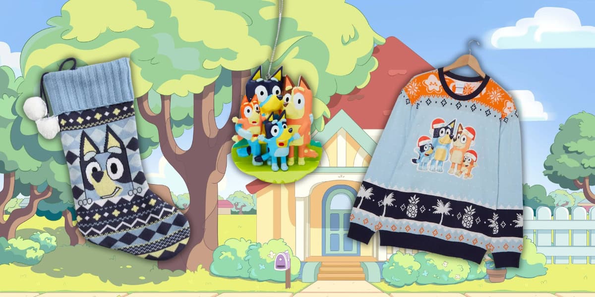 A colorful display features a festive stocking and a Bluey-themed sweater adorned with cartoon dog characters, alongside matching ornaments. The backdrop is an animated suburban scene with trees and a house, capturing the playful essence of Bluey.