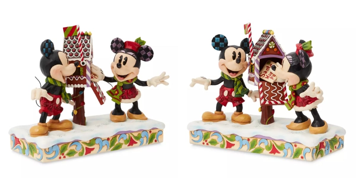 Two Jim Shore figurines of Mickey and Minnie Mouse, dressed in festive attire, stand by a decorative gingerbread mailbox. One is opening the mailbox, both poised on a colorful, winter-themed base that captures the enchanting spirit of the season.