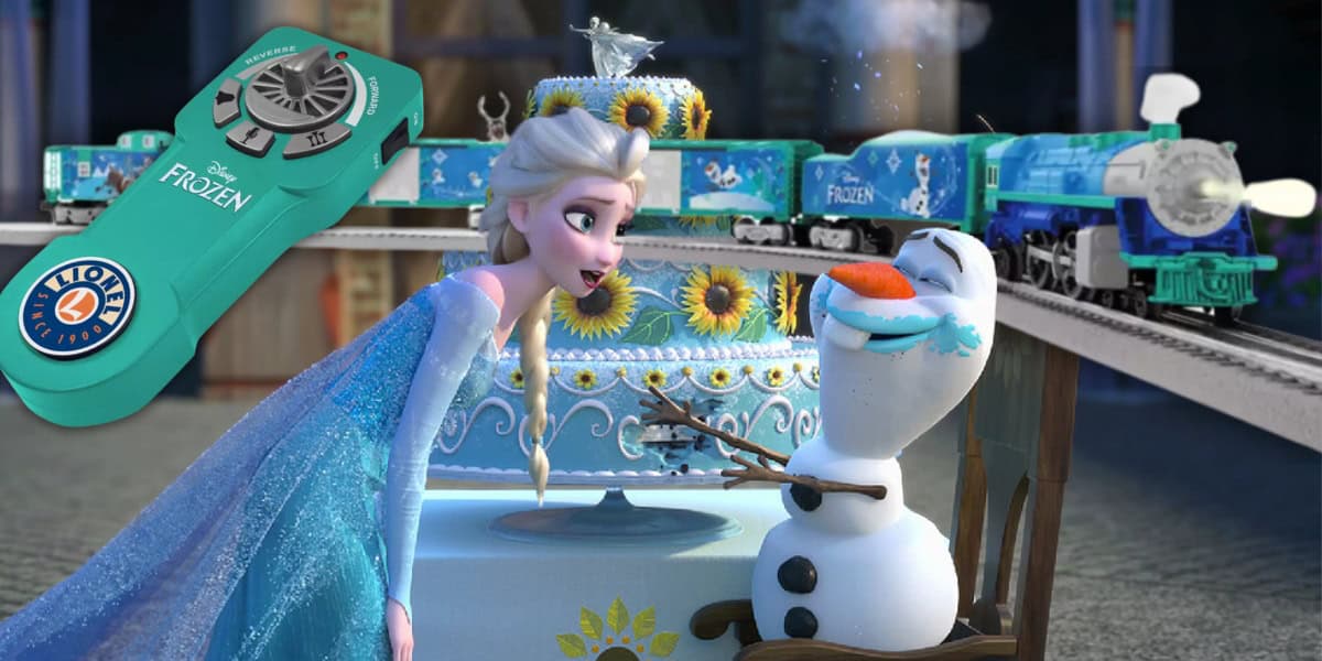 A scene from the animated movie "Frozen" shows Elsa leaning playfully toward Olaf, who sits excitedly by a large cake. In the background, a Frozen-themed LionChief Train Set chugs along, adding magic to the moment with its vibrant craftsmanship and charm.