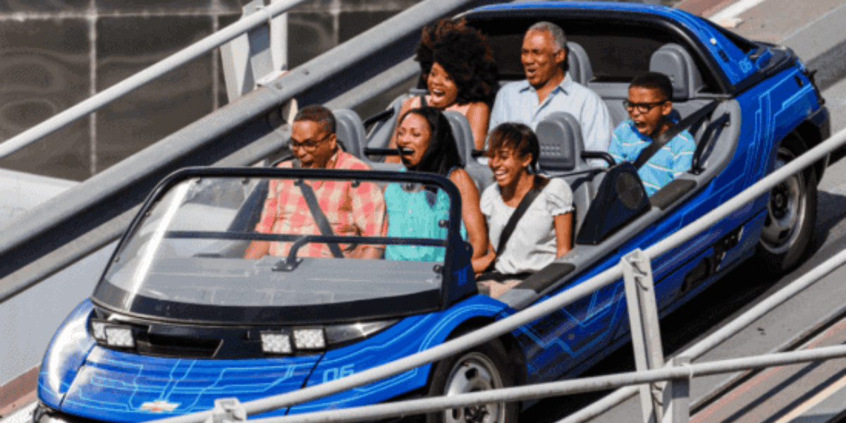 Six Guests grinning as a car drives them at top speed on Chevrolet Test Track - a Walt Disney World ride.