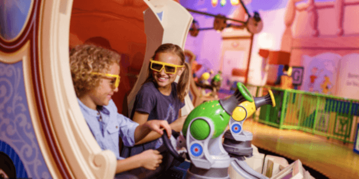 A little boy and a little girl smile while wearing 3D glasses on Toy Story Midway Mania.