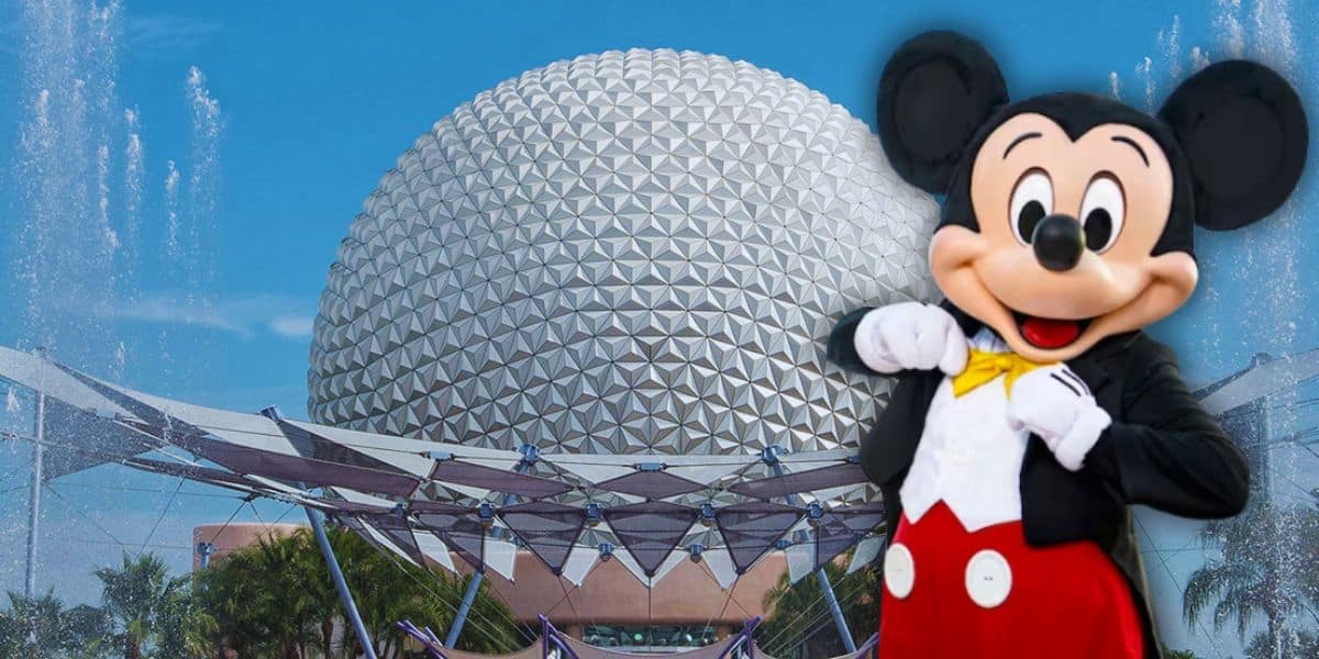 Mickey Mouse stands in front of the iconic geodesic sphere at EPCOT, showcasing a charming Disney Loungefly Bag against a clear blue sky and fountains at Disney World.