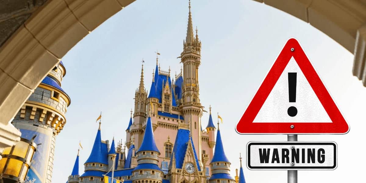 An iconic castle with blue and gold accents is framed by a stone archway. In the foreground, a red triangular warning sign with an exclamation mark signals "Warning," alerting visitors to Hurricane Milton's approach near Disney World.