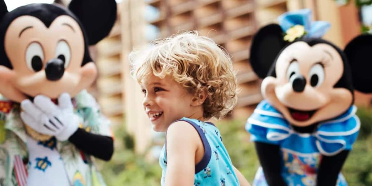 A child smiling with Mickey and Minnie at Disney Aulani