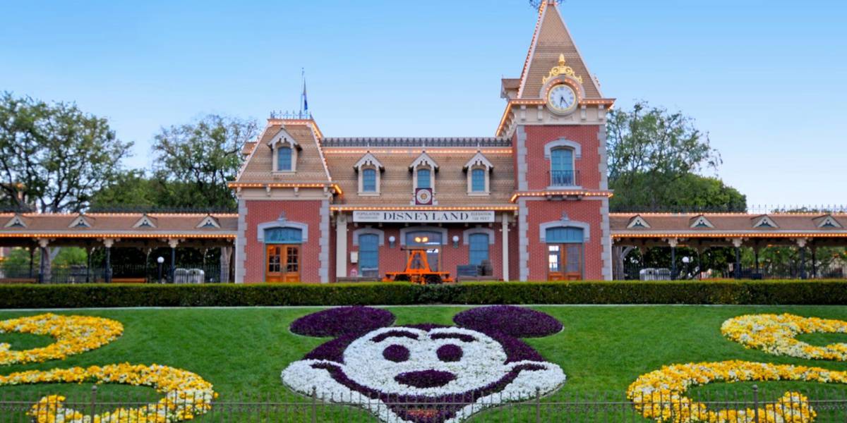 A Mickey Mouse head made of flowers in front of the Disneyland Railroad