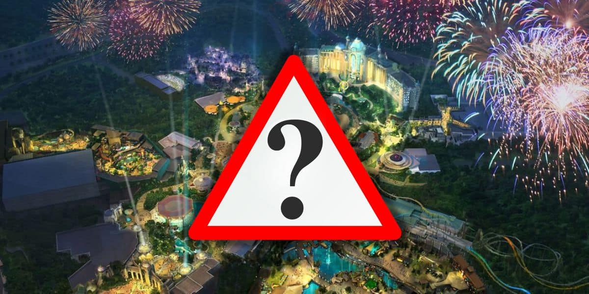 An aerial view of the Epic Universe theme park at night shows it illuminated with various lights and vibrant fireworks in the sky. The park appears bustling with attractions, rides, and green areas. A large warning sign with a question mark is superimposed in the center at Universal Orlando Resort.