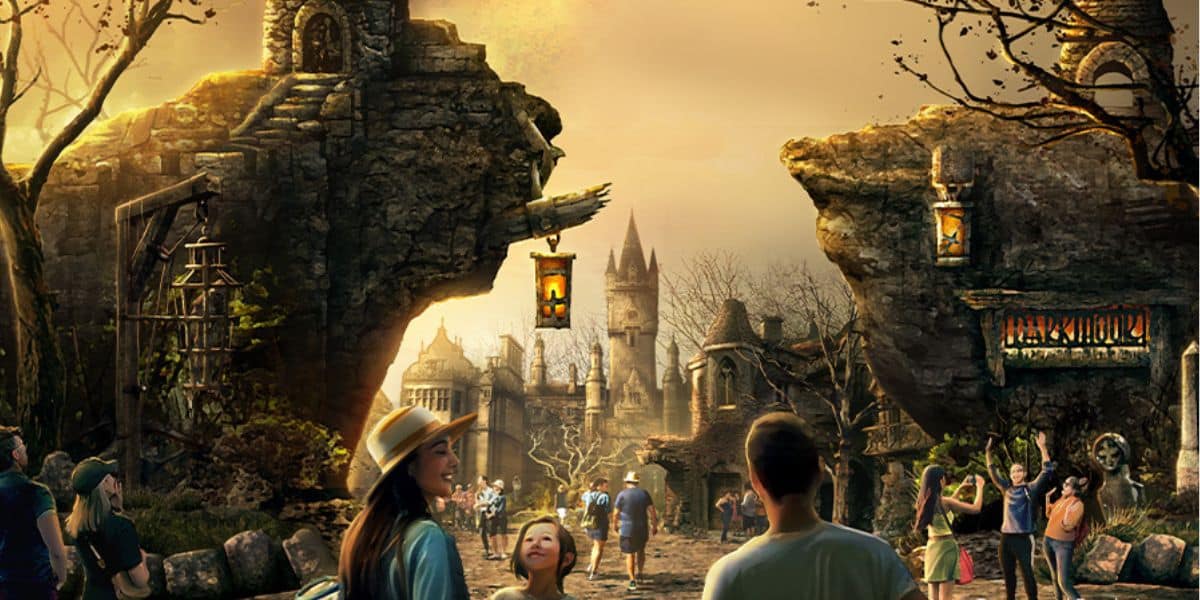 A whimsical, fantasy setting with people exploring. The scene features large rock formations with lanterns, a castle-like building in the background, and a golden sunset casting a warm glow. Trees and vegetation accentuate the enchanting atmosphere of this villainous-themed land imside Epic Universe at Universal Orlando Resort.