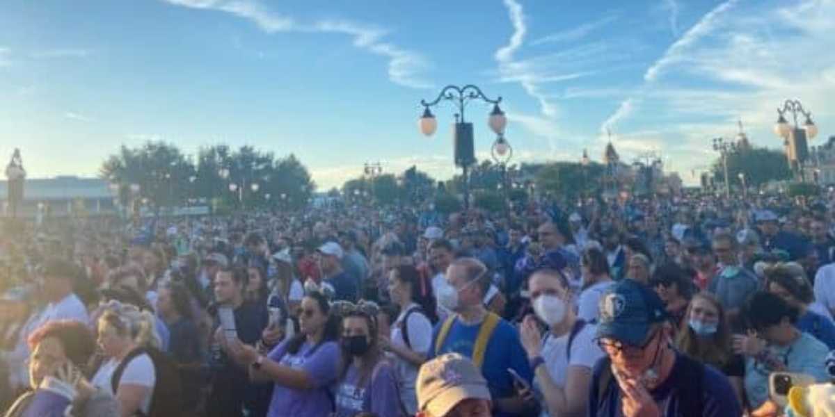 A large crowd of people swarming the entrance to Magic Kingdom during the early morning hours at Disney World.