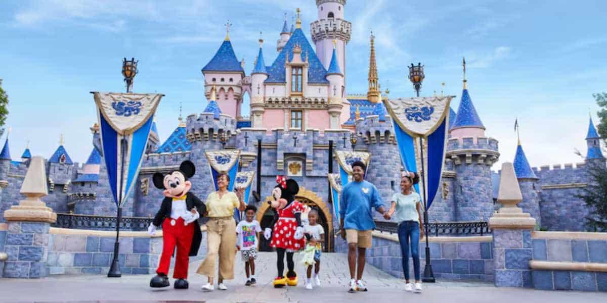 Mickey and Minnie walk with a family in front of Sleeping Beauty Castle at Disneyland Park in Anaheim, California.