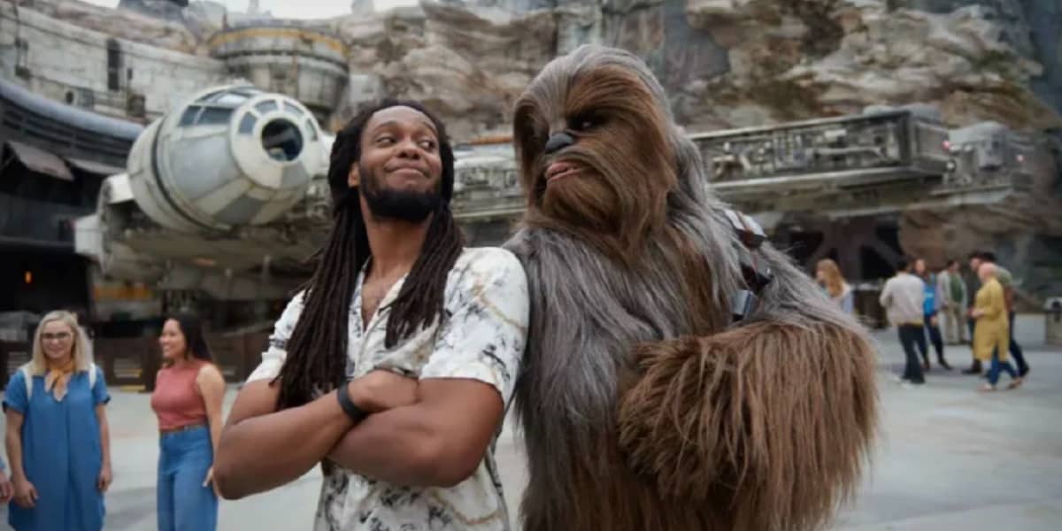 A guest standing back to back with Chewbacca at Star Wars Galaxy's Edge