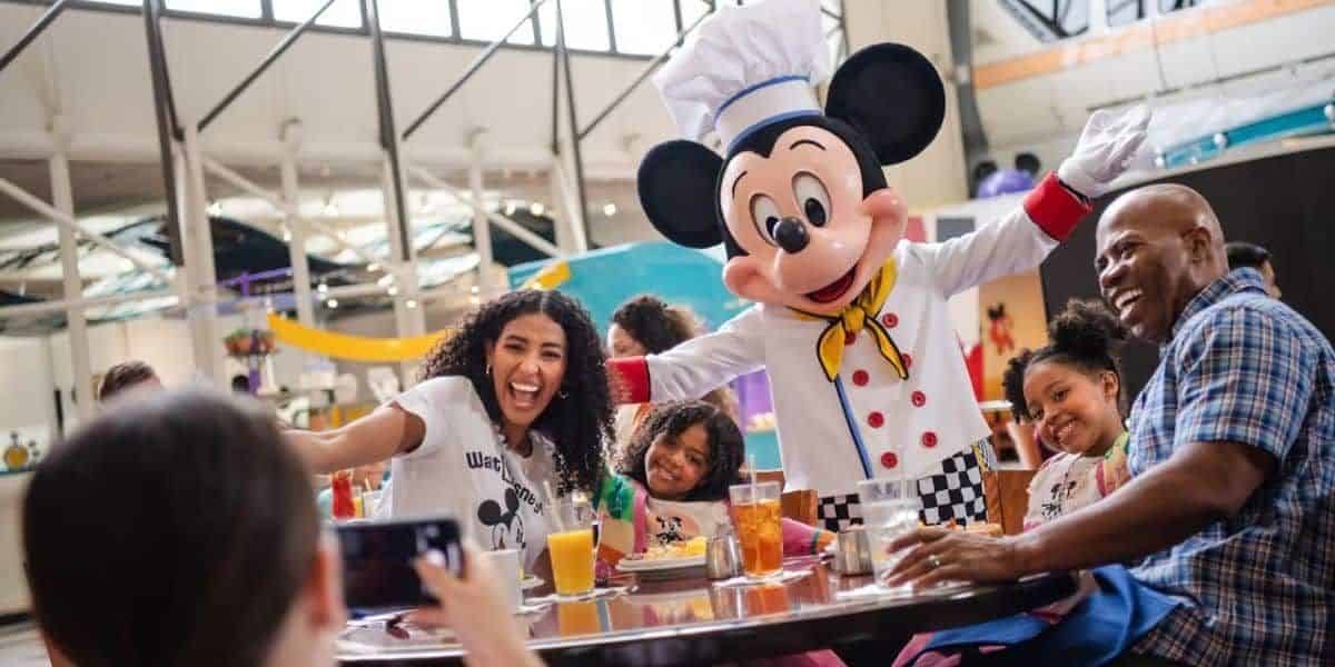 A family sits at a table as they meet Mickey Mouse as Chef Mickey's in the Contemporary Resort