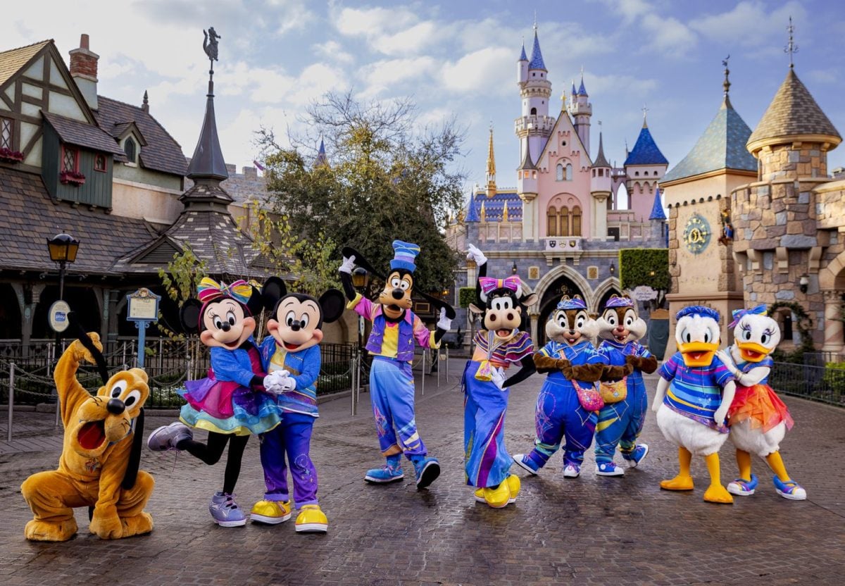 Disney Characters Disneyland 70th Anniversary Outfits in front of the Disney castle.