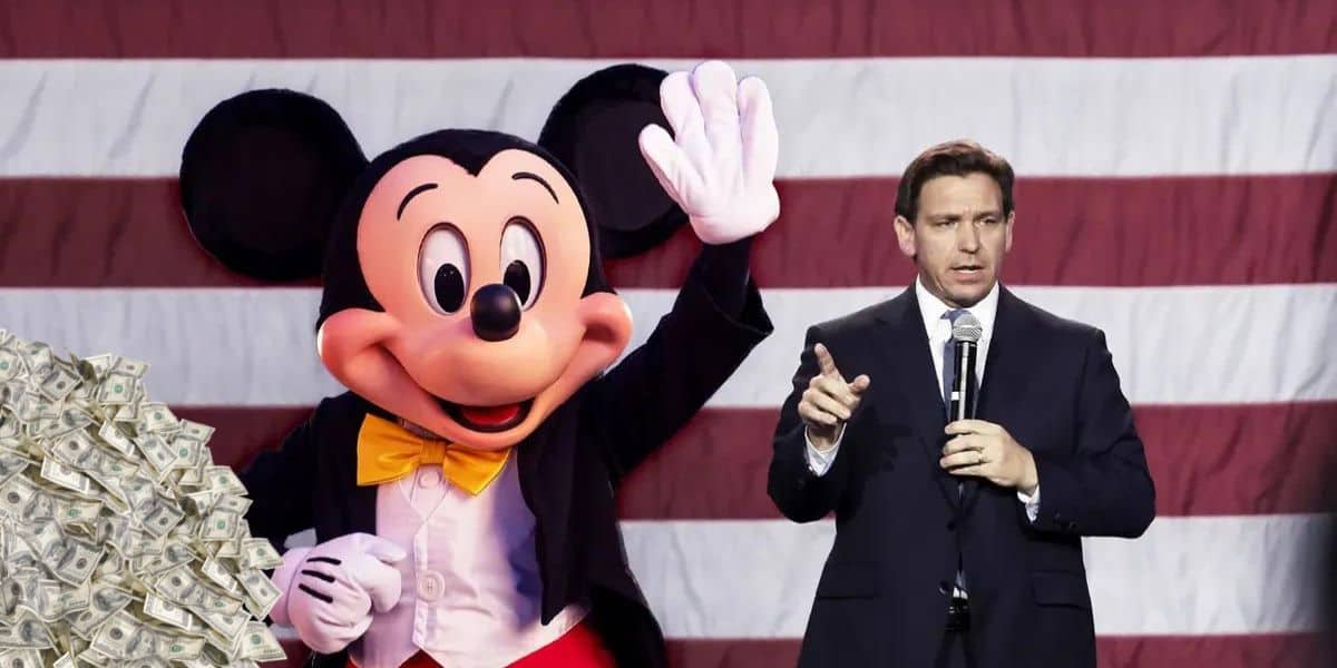 A person in a suit holding a microphone stands next to a person dressed as Mickey Mouse, who is waving. In the background, there is a large American flag. To the left, there is a large pile of money, reminiscent of Ron DeSantis's campaign events.