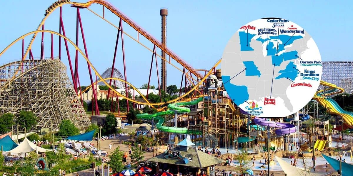 A vibrant amusement park with various roller coasters, water slides, and attractions. An inset map highlights locations of different theme parks such as Cedar Point, Canada's Wonderland, Kings Island, and others across North America as part of the new Six Flags Entertainment merger.