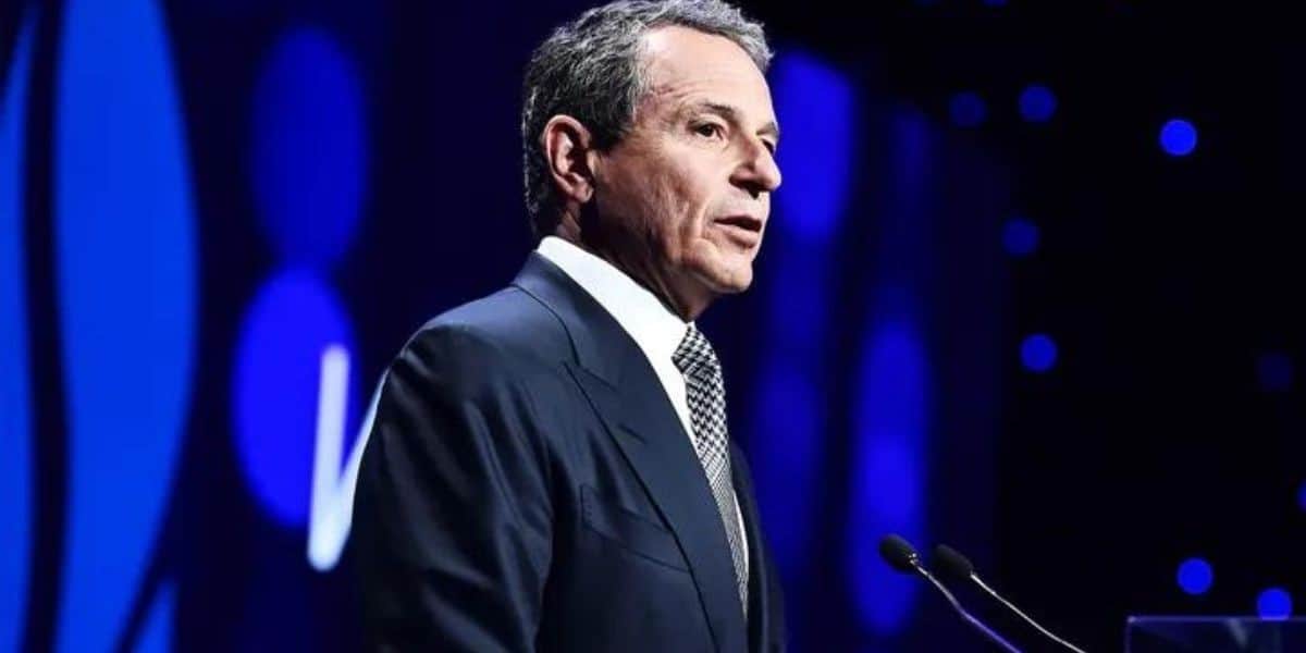 Bob Iger speaking at a podium against a blue-lit backdrop.