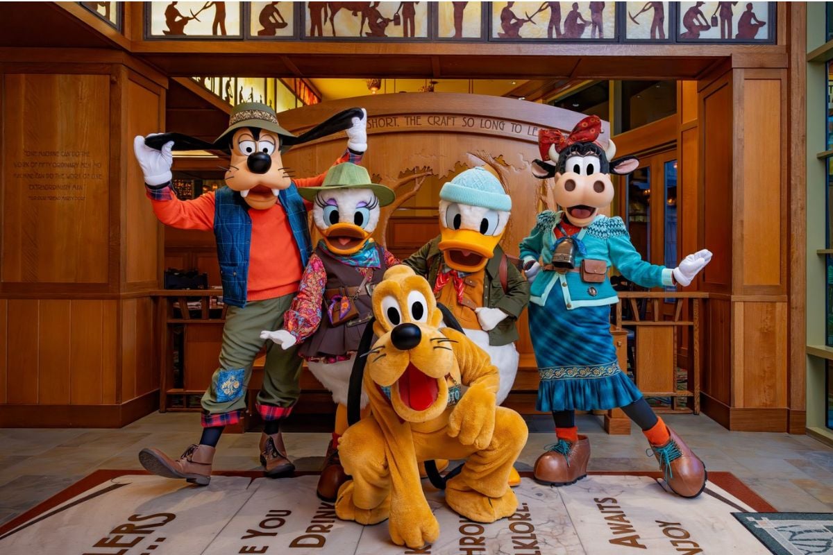 Goofy, Daisy Duck, Donald Duck, Clarabelle Cow, and Pluto pose in colorful camping outfits at Storytellers Cafe.