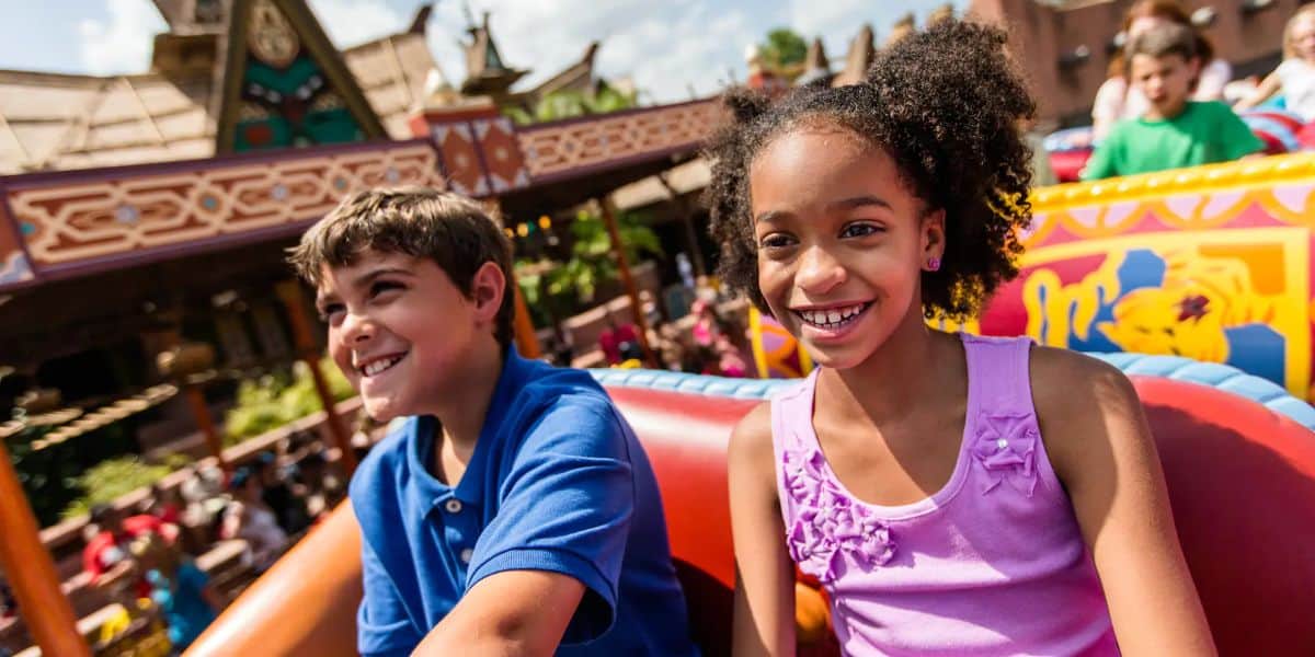 A young boy and girl smile while riding the Magic Carpets of Aladdin