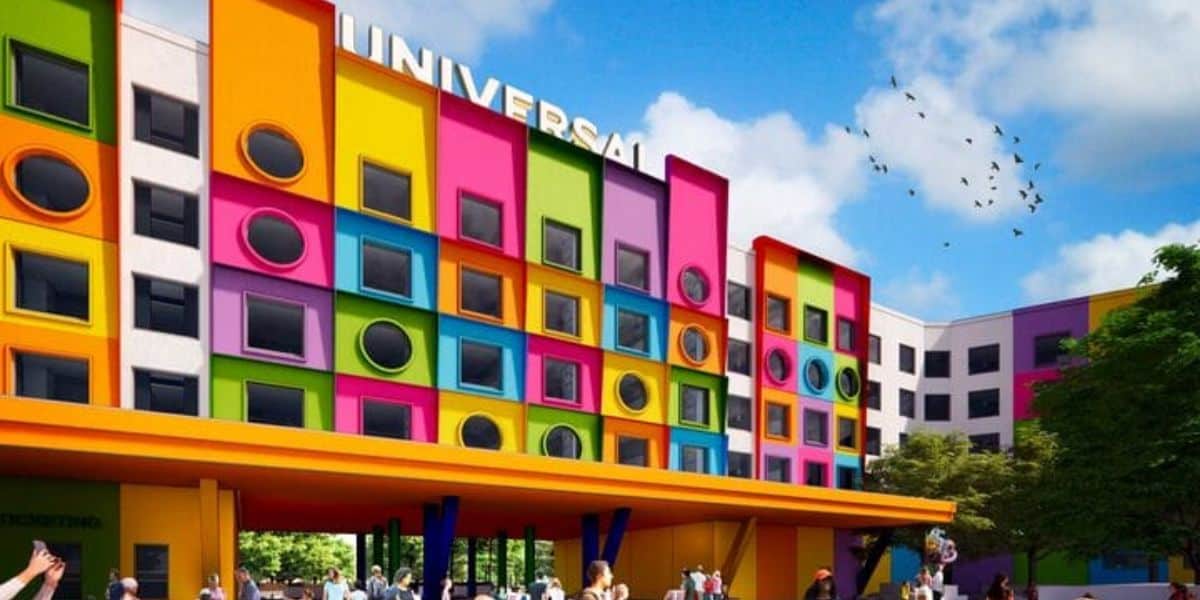 A colorful Universal building in Texas features vibrant square and circular windows, a yellow canopy, and people gathered outside; trees and birds fill the bright theme park sky.