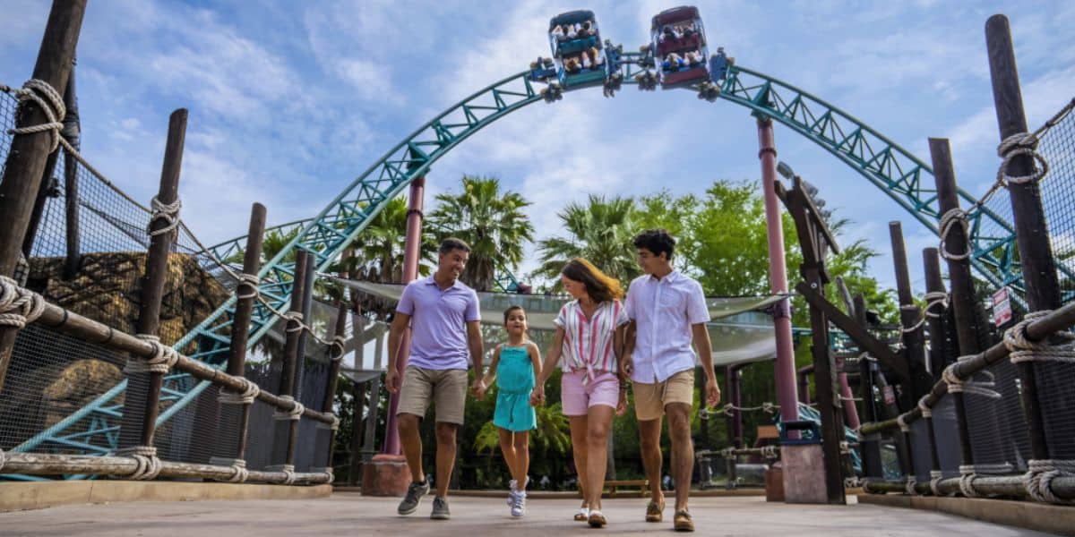 A family walking through Busch Gardens Tampa Bay with a roller coaster in the background at this Florida theme park.