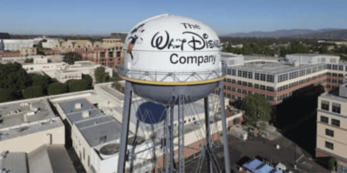 Aerial view of the Walt Disney Company water tower, proudly showcasing its logo. The iconic tower stands amidst office buildings and lush greenery under a clear blue sky, evoking a sense of timeless magic even in the digital age.
