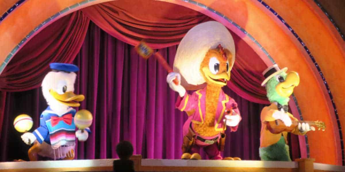 Mark your calendars, Disney fans! On September 3, three animatronic characters perform on a colorful stage with red curtains. From left to right, there's a duck wearing a blue hat and holding maracas, a bird in a sombrero holding a baton, and a turtle playing a guitar and wearing a hat.