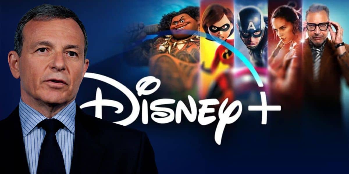 A man in a suit stands in front of the Disney+ logo, surrounded by beloved Disney characters including Moana, Mrs. Incredible, Captain America, Rey from Star Wars, and Jeff Goldblum's character from Jurassic Park. The backdrop is a stunning gradient of blues and purples.