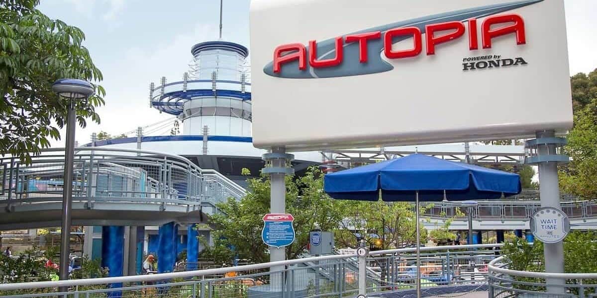 Entrance to Autopia, the classic car-themed attraction, with futuristic structures in the background under a clear sky.