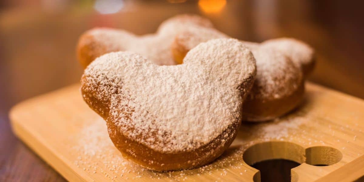 Three Mickey Mouse-shaped beignets stacked up against each other.