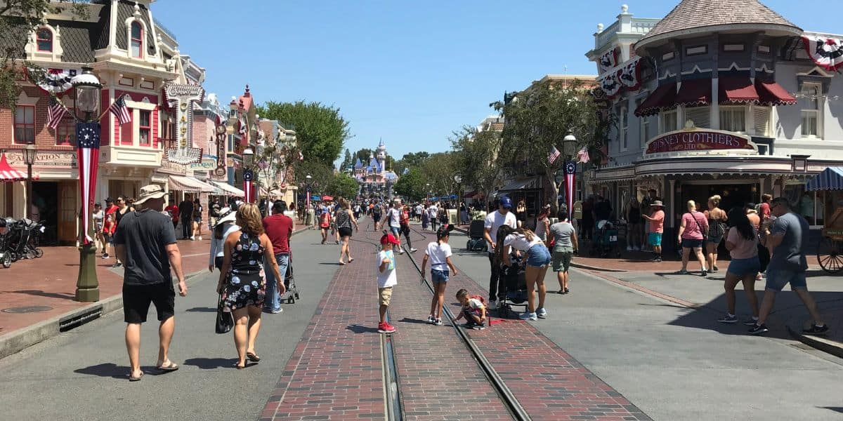 Disney Park Guests on Main Street, U.S.A. at Disneyland Park on a clear blue-sky day.