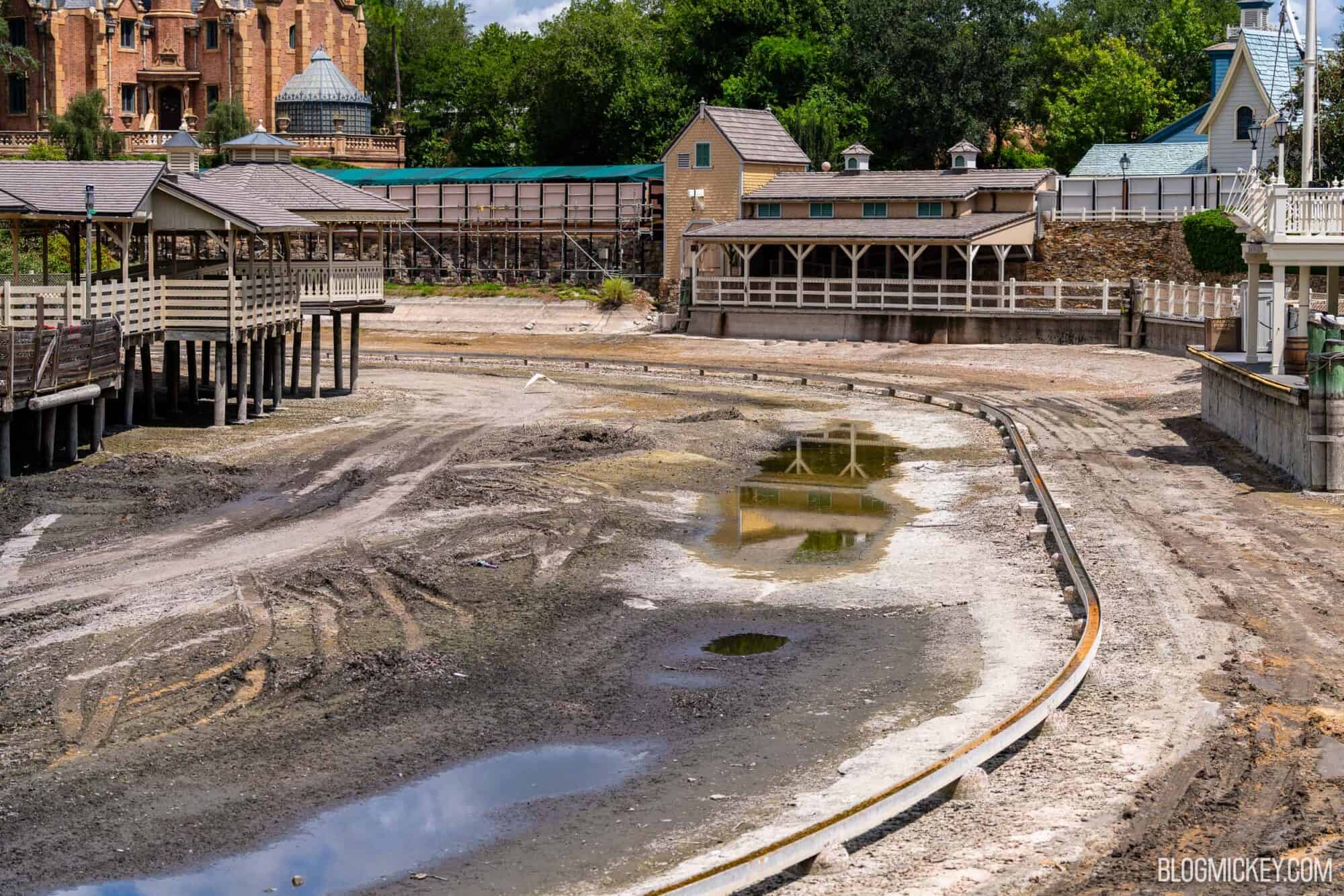 Drained Rivers of America with exposed ride track. A partial view of The Haunted Mansion is visible in the distance