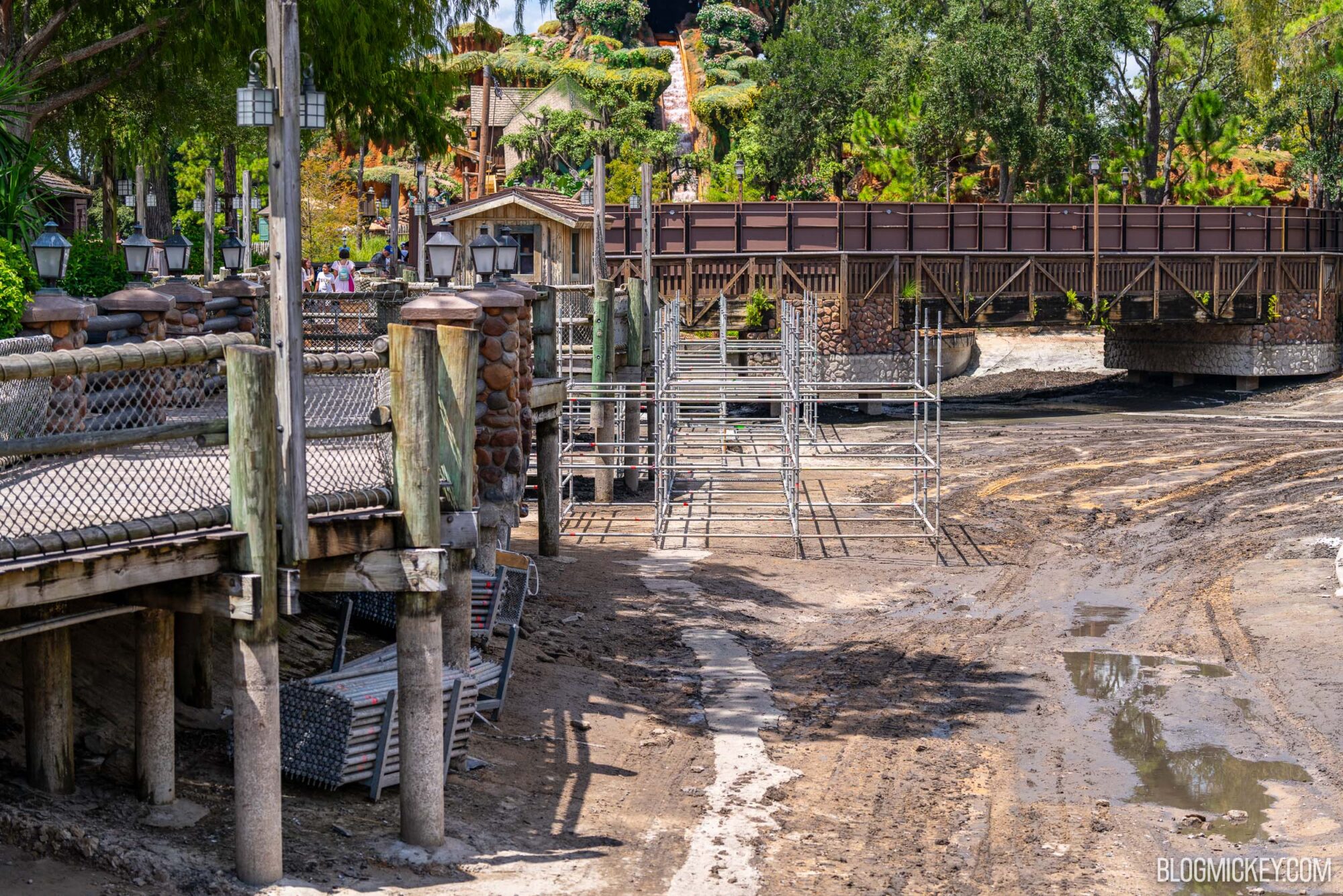 Scaffolding and construction area in the dried Rivers of America, with wooden pathways, lush greenery, and ongoing work. Photo captures the development of new attractions