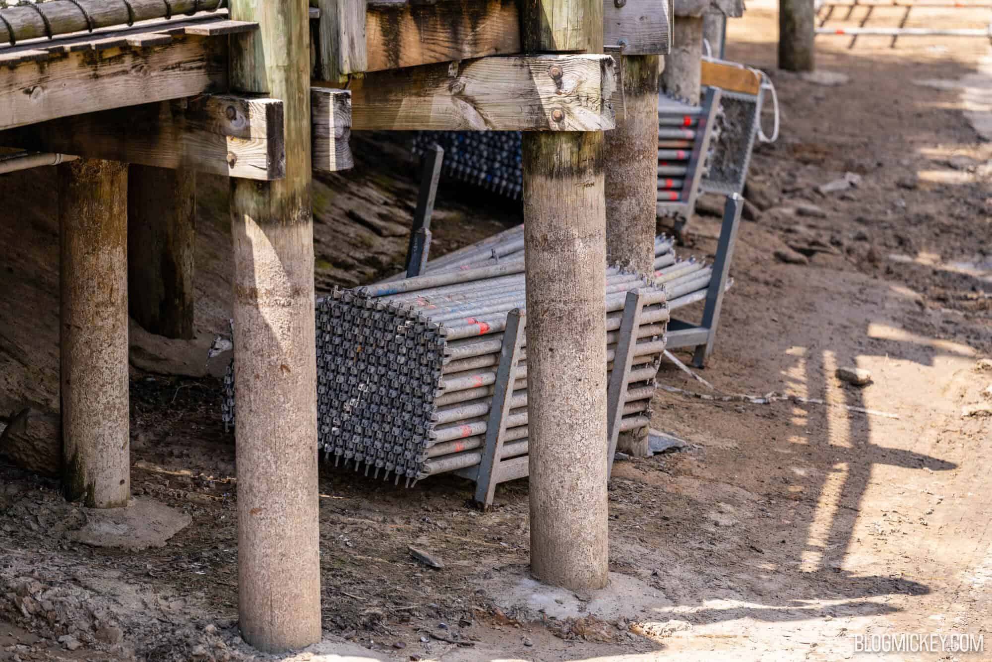 Metal scaffolding piled up under a wooden boardwalk, ready to be installed during overnight work in the dried Rivers of America