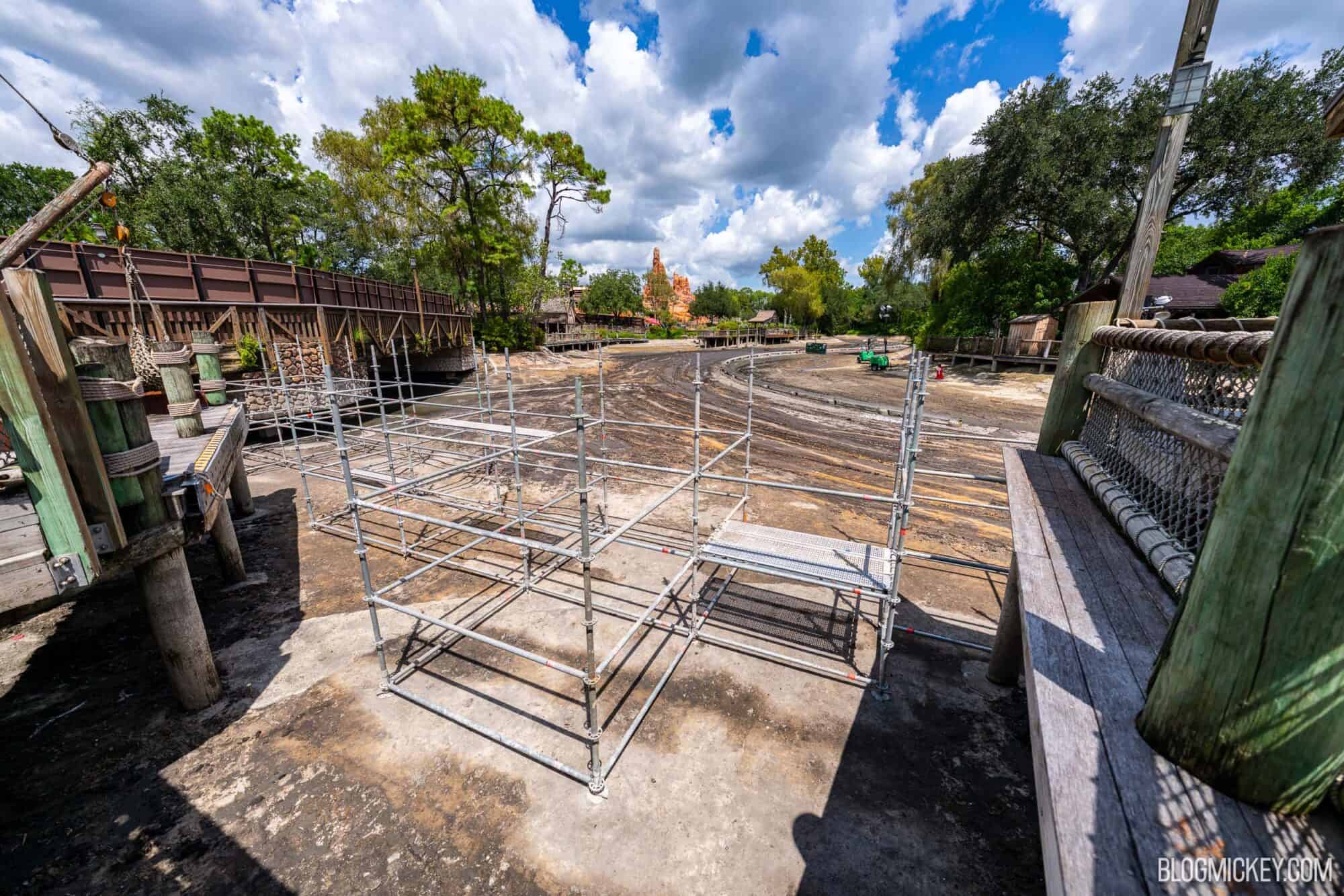 Drained Rivers of America riverbed with ongoing scaffolding constrcution near a wooden boardwalk