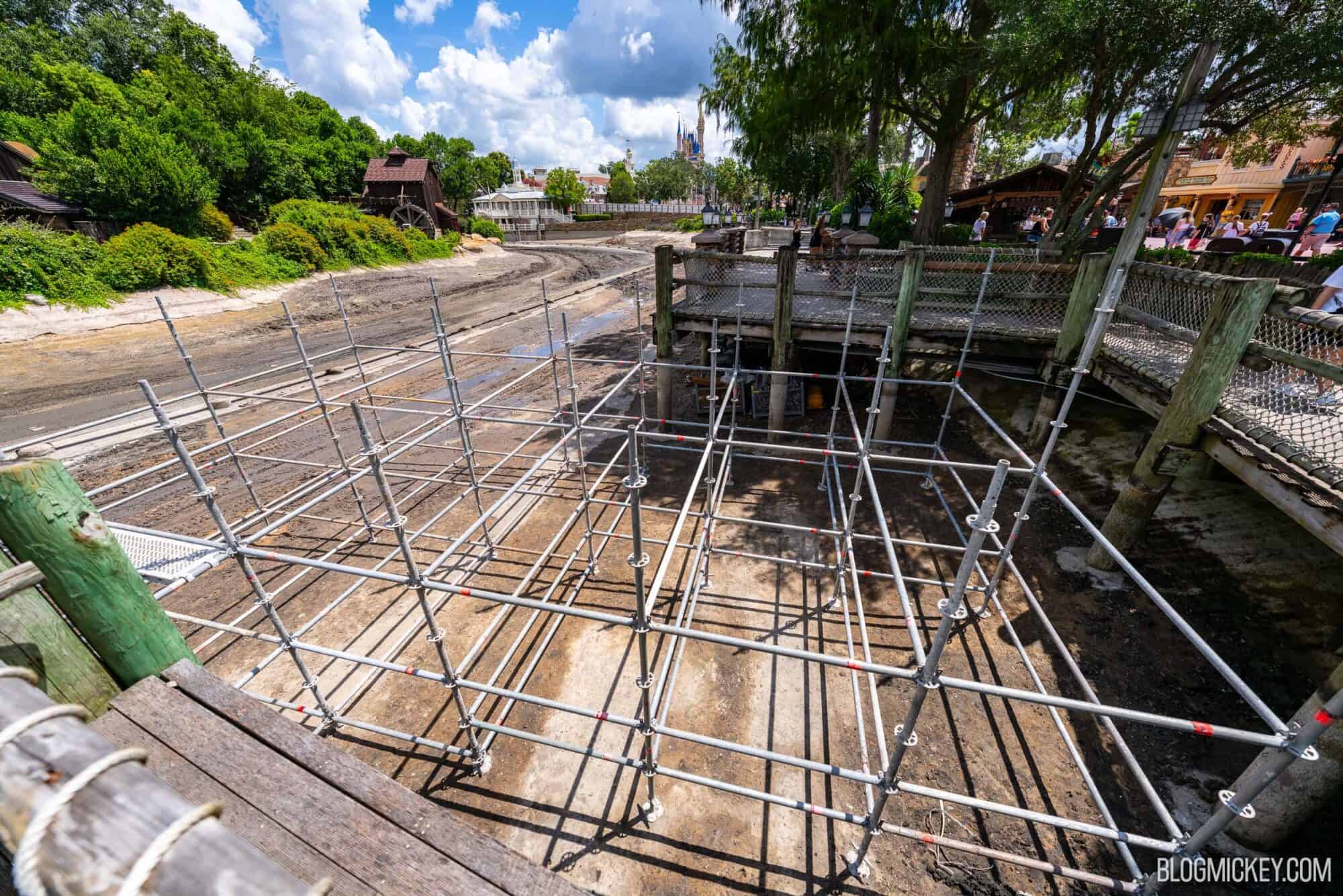 Drained Rivers of America riverbed with ongoing scaffolding constrcution near a wooden boardwalk