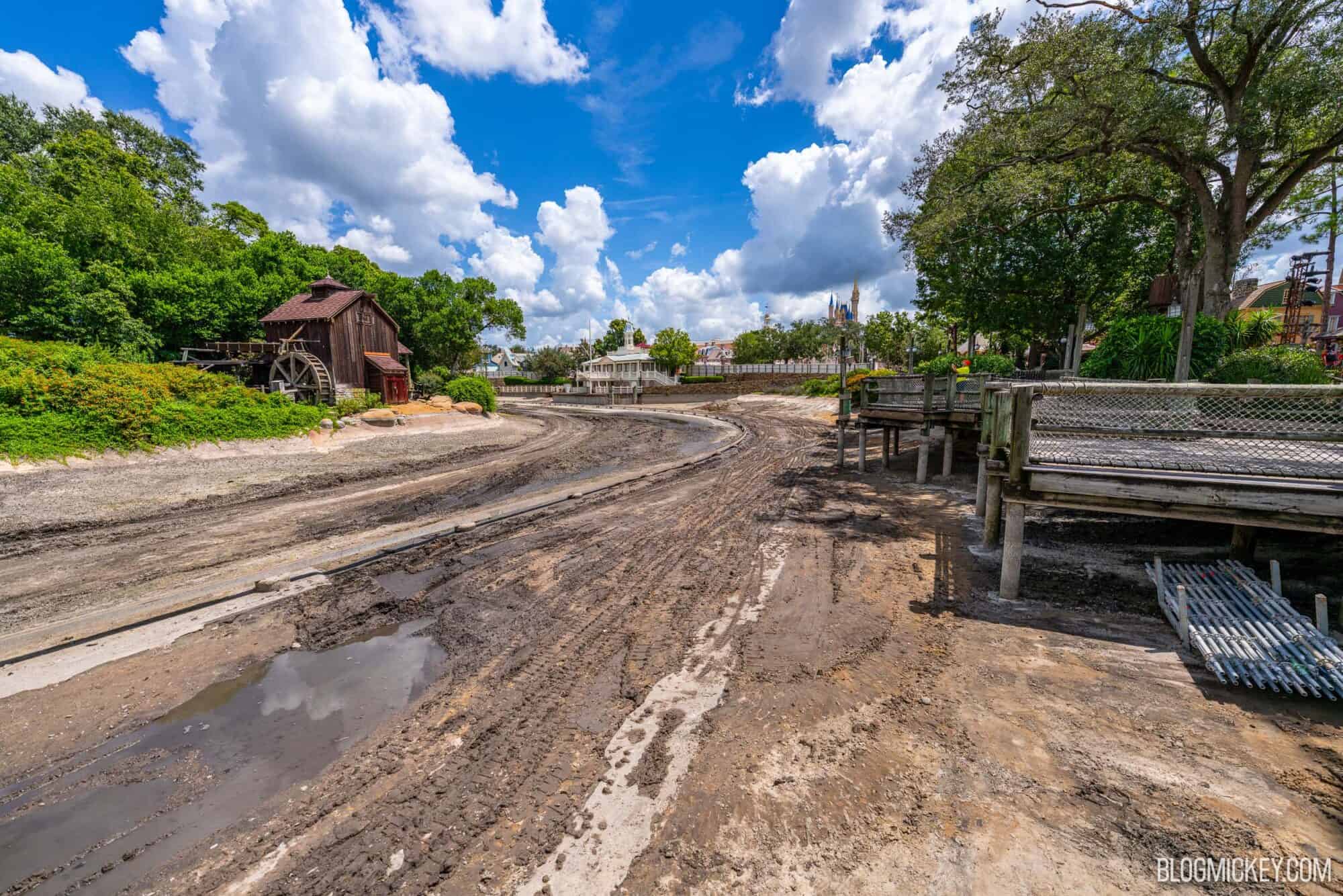 Drained Rivers of America with exposed ride track. A lush Tom Sawyer Island sits on the other side of the drained river basin