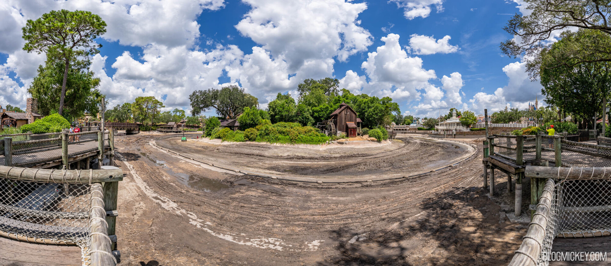 Drained Rivers of America with exposed ride track. A lush Tom Sawyer Island sits on the other side of the drained river basin
